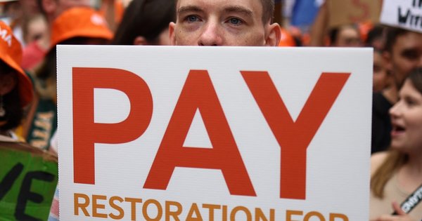 A demonstrator holds a placard during a protest calling for better pay for Junior Doctors in Whitehall, outside the gates of Downing Street in central London on August 11, 2023