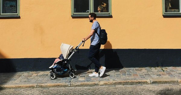 Man walks in a city street with a pushchair