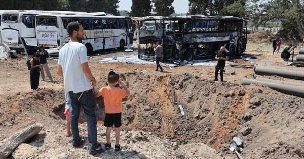 Onlookers stand in front of a crater at the impact site of an Iranian missile at a bus depot in Herzliya near Tel Aviv on 17 June 2025.
