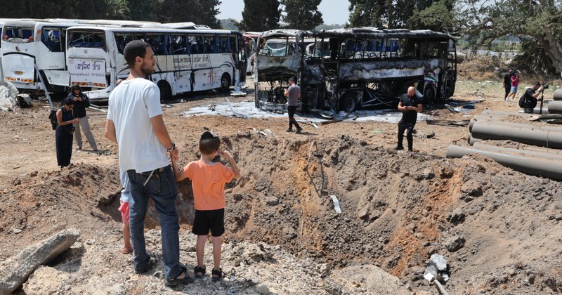 Onlookers stand in front of a crater at the impact site of an Iranian missile at a bus depot in Herzliya near Tel Aviv on 17 June 2025.